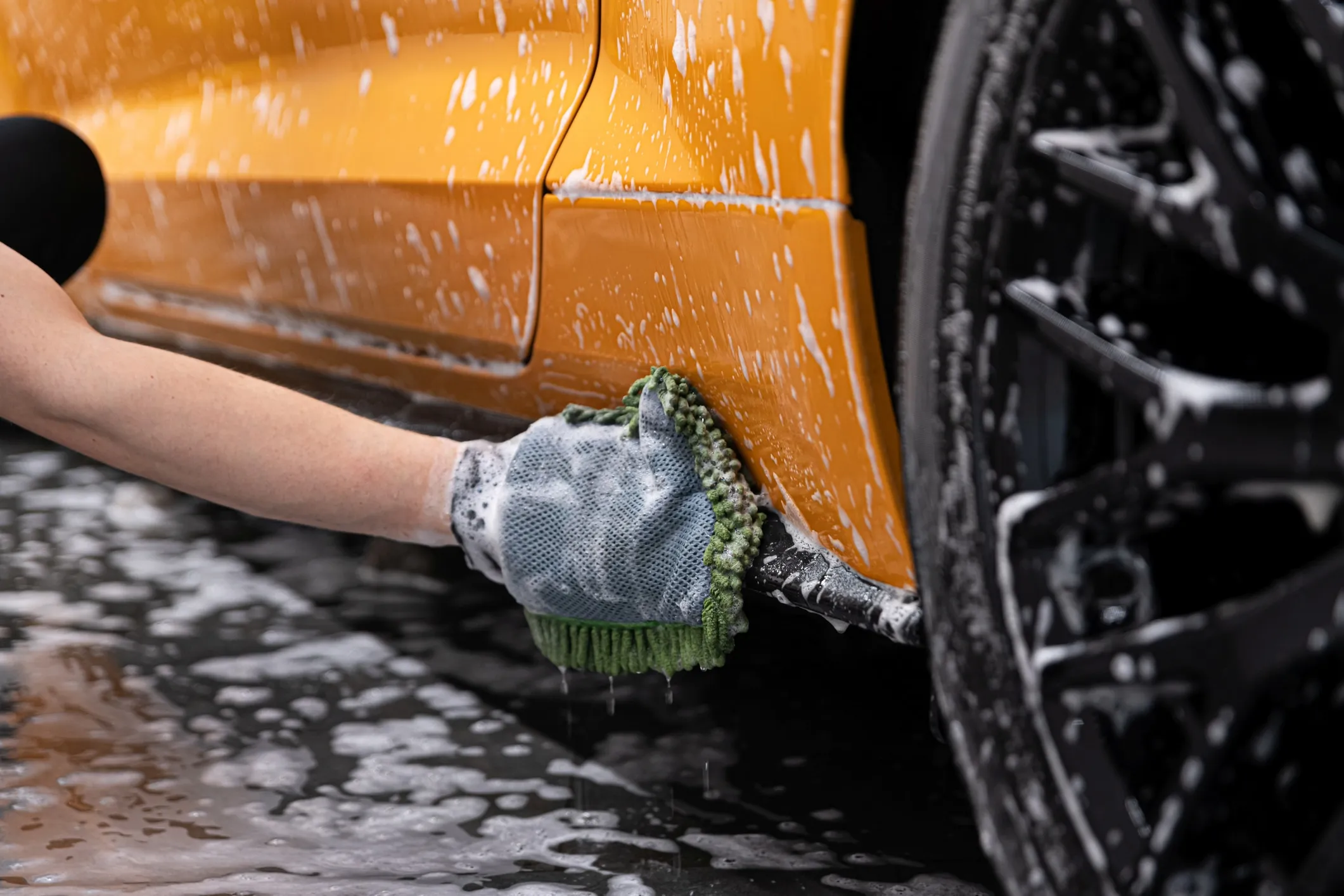 Hand washing a car wheel with a wash mitt